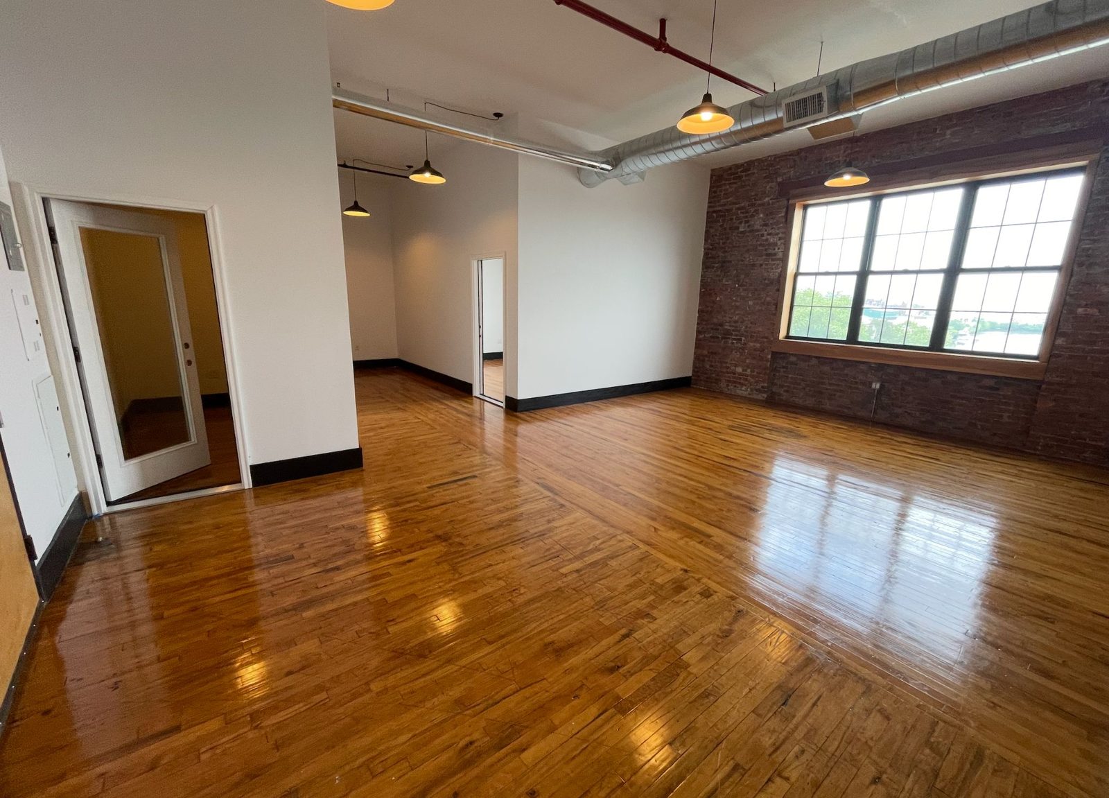 Unit 400 open floor area with brick accent wall and natural light
