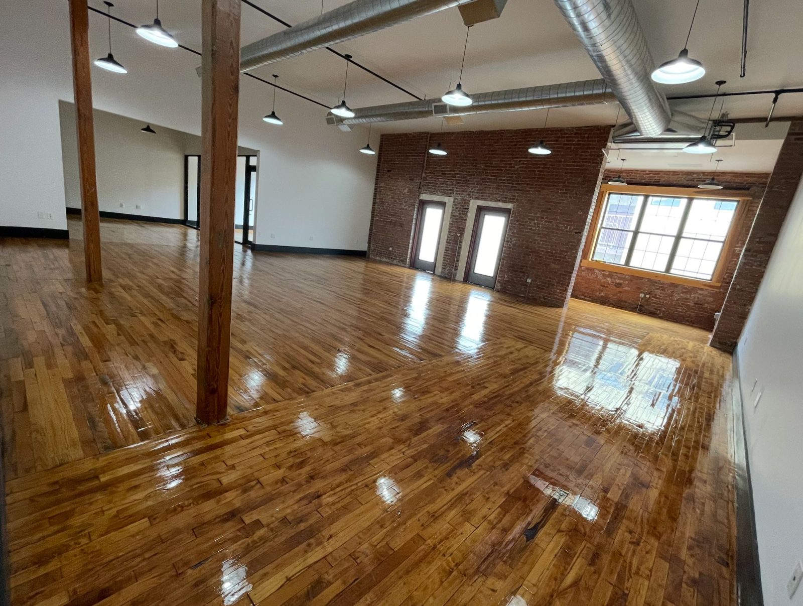 Unit 420/424 open loft with timber columns, exposed ductwork and a brick wall